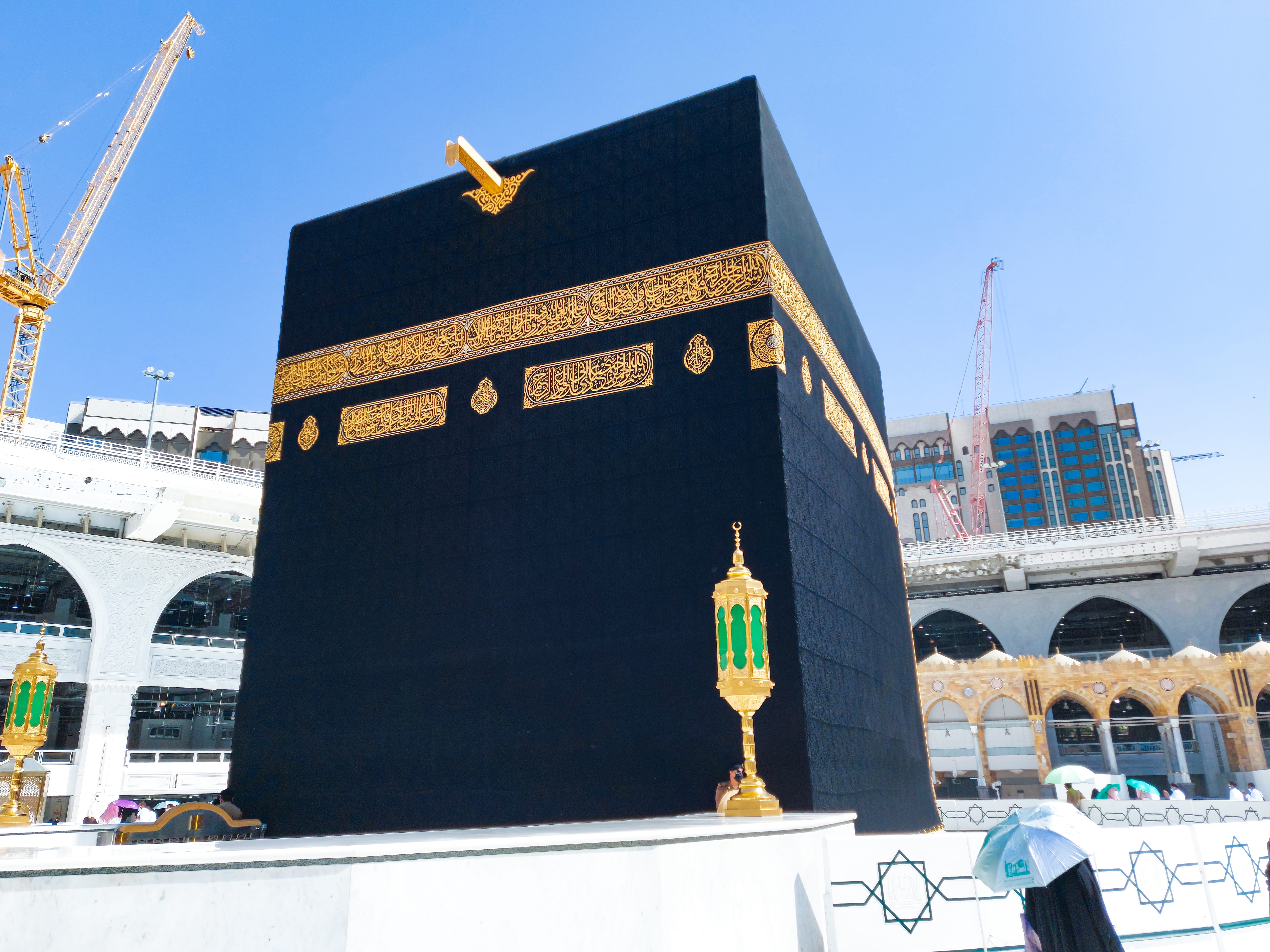 Islamic holy site Kaaba in Masjid al-Haram, Mecca, Saudi Arabia, with pilgrims and Abraj Al Bait Clock Tower view
