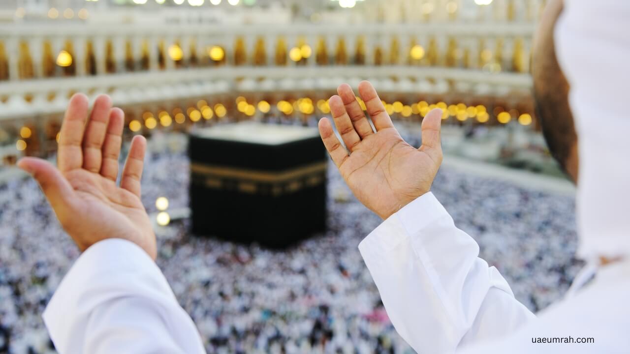 A Muslim pilgrim raising hands in prayer facing the Holy Kaaba in Masjid al-Haram, Makkah during Umrah.